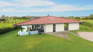 A single-story building with a red-tiled roof, a covered patio area, and a grassy lawn. - Beach front home in Sydals with WiFi (Sydals)