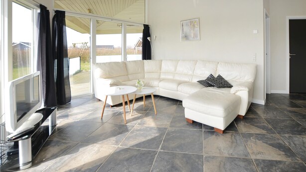 A modern living room with a white sectional sofa, a small round table, and a TV. - Beach front home in Sydals with WiFi (Sydals)