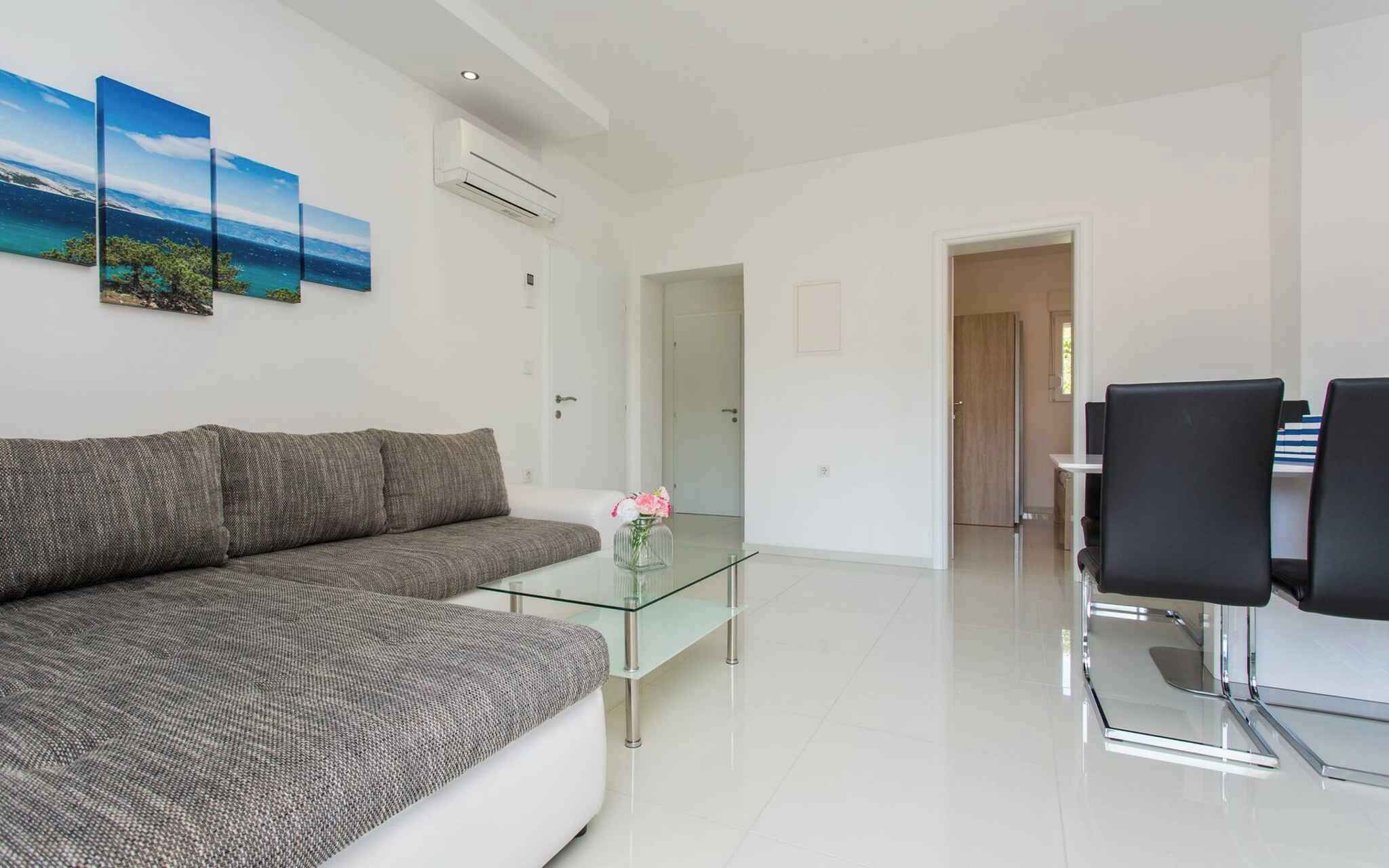 Una sala de estar moderna con un sofá gris, una mesa de centro de vidrio y un comedor con sillas negras.