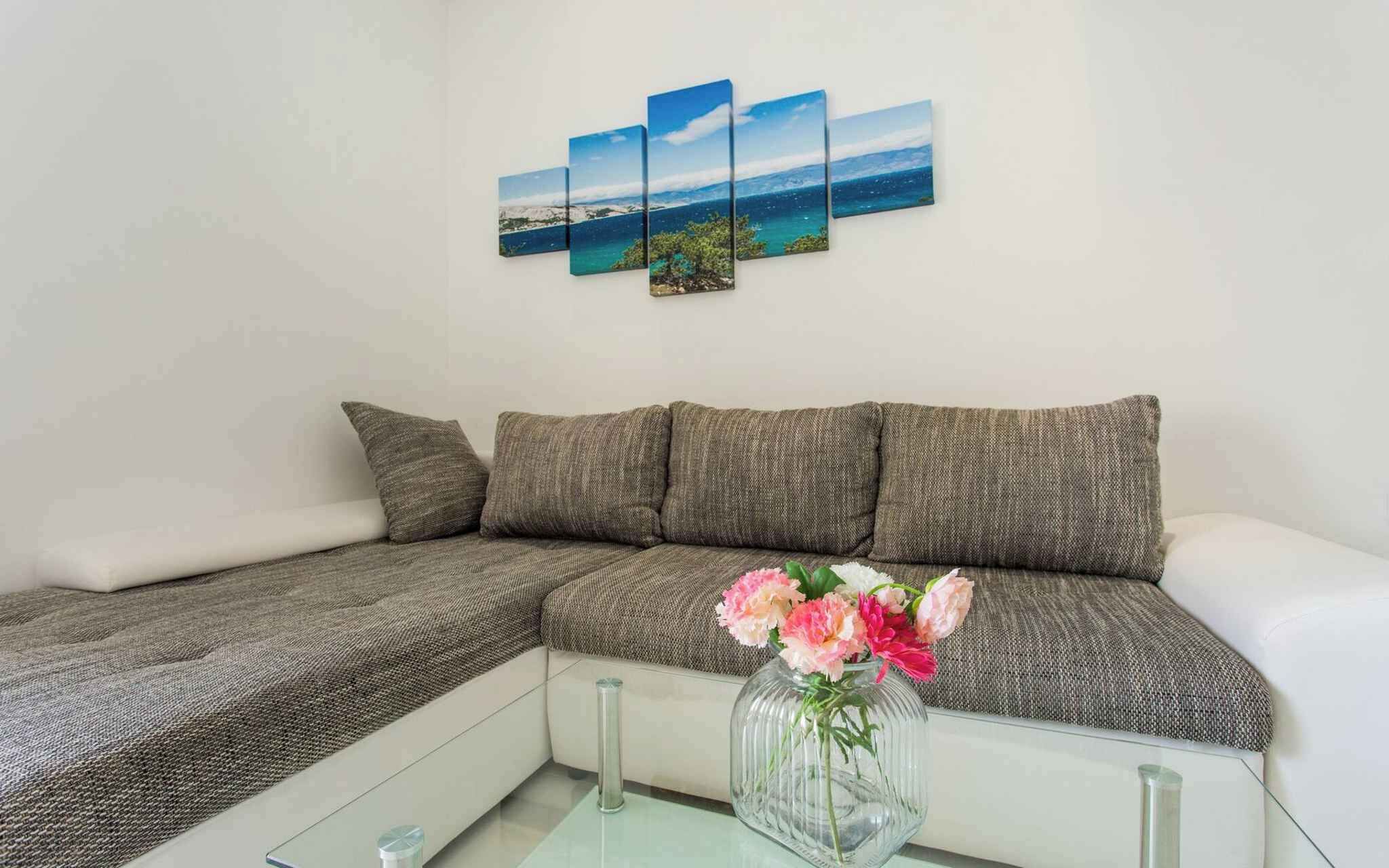 Una sala de estar moderna con un sofá seccional, una mesa de centro de vidrio y un jarrón con flores.