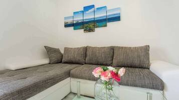 Una sala de estar moderna con un sofá seccional, una mesa de centro de vidrio y un jarrón con flores.