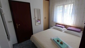 Une chambre à coucher avec un lit, une armoire, un miroir et une fenêtre avec des rideaux.