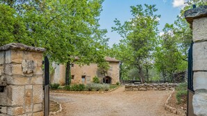 A rustic stone building with a dirt path leading to it, surrounded by trees.