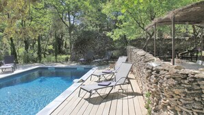 A pool area with lounge chairs and a stone wall.