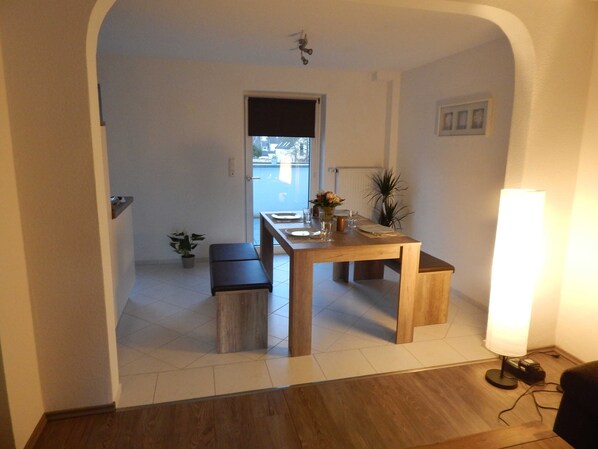 Uma sala de jantar com uma mesa de madeira, bancos e plantas em vasos.