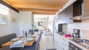 A modern kitchen with a dining area, wooden ceiling, and a view to a living room. - Gorgeous home in Lazise VR (Lazise VR)