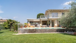 A two-story house with a swimming pool, stone walls, and outdoor seating. - Gorgeous home in Lazise VR (Lazise VR)