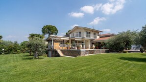 A two-story house with a stone foundation, a balcony, and a well-maintained lawn. - Gorgeous home in Lazise VR (Lazise VR)