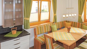 A cozy kitchen with a dining area, featuring striped cushions, a wooden table, and a wicker basket on the counter.