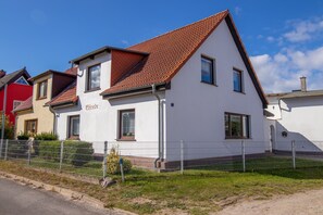 A two-story house with a red-tiled roof, a white exterior, and a visible nameplate. - Elfriede house rental (Kröslin)