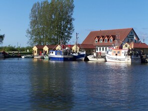 A row of boats docked at a marina with a building in the background.