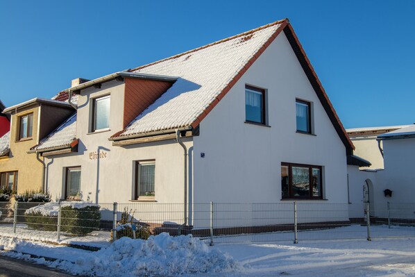 A two-story house with a sloped roof, a visible chimney, and a small window.