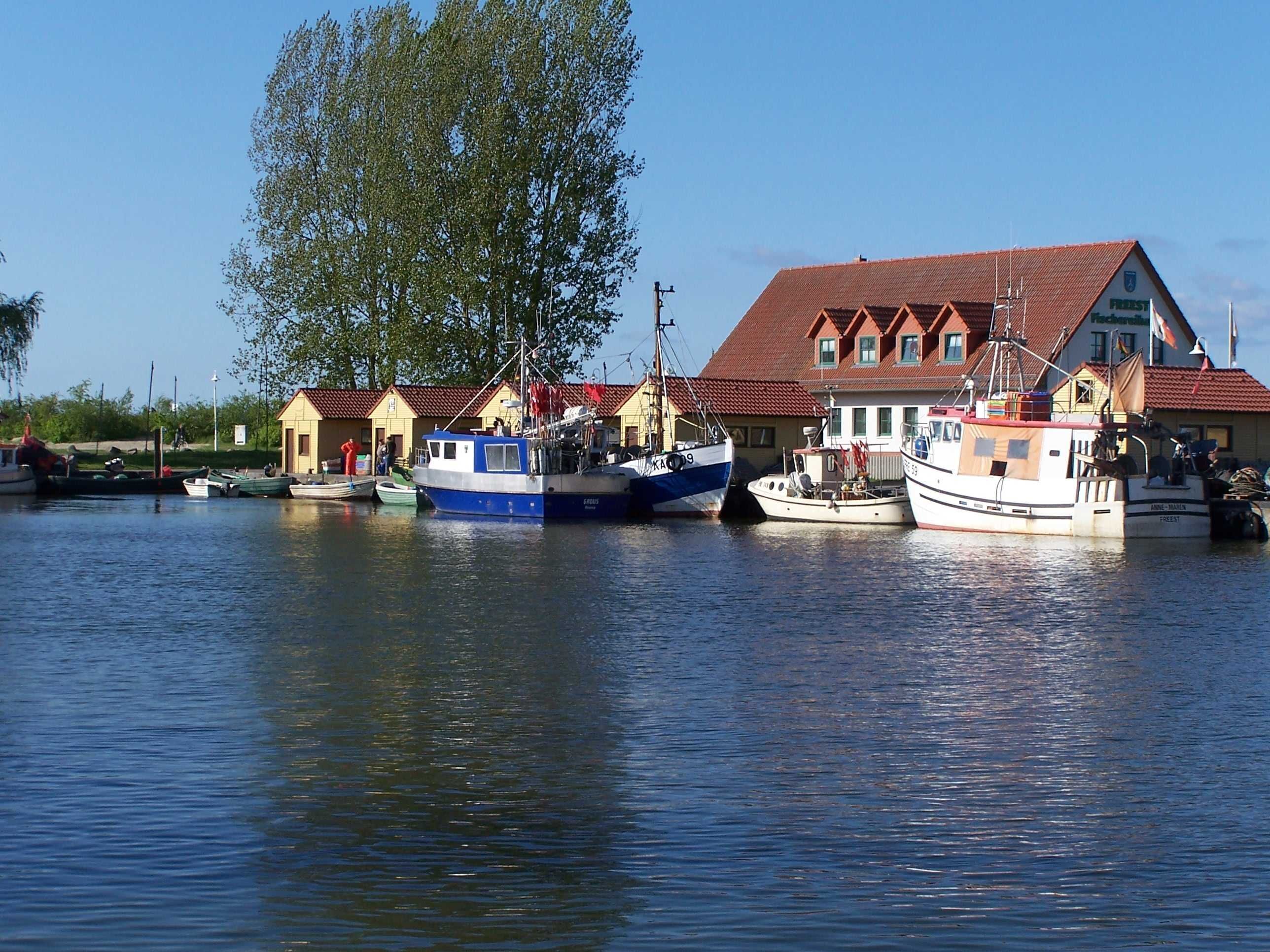 Eine Reihe von Booten liegt in einer Marina vor einem Gebäude.