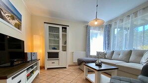 A living room with a television, sofa, and a table. - Dünenresidenz Karlshagen, Sanddornweg 1a, - WE Sanddornweg 1a (Karlshagen)