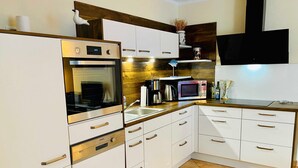 A modern kitchen with white cabinets, stainless steel appliances, and a wooden countertop. - Dünenresidenz Karlshagen, Sanddornweg 1a, - WE Sanddornweg 1a (Karlshagen)