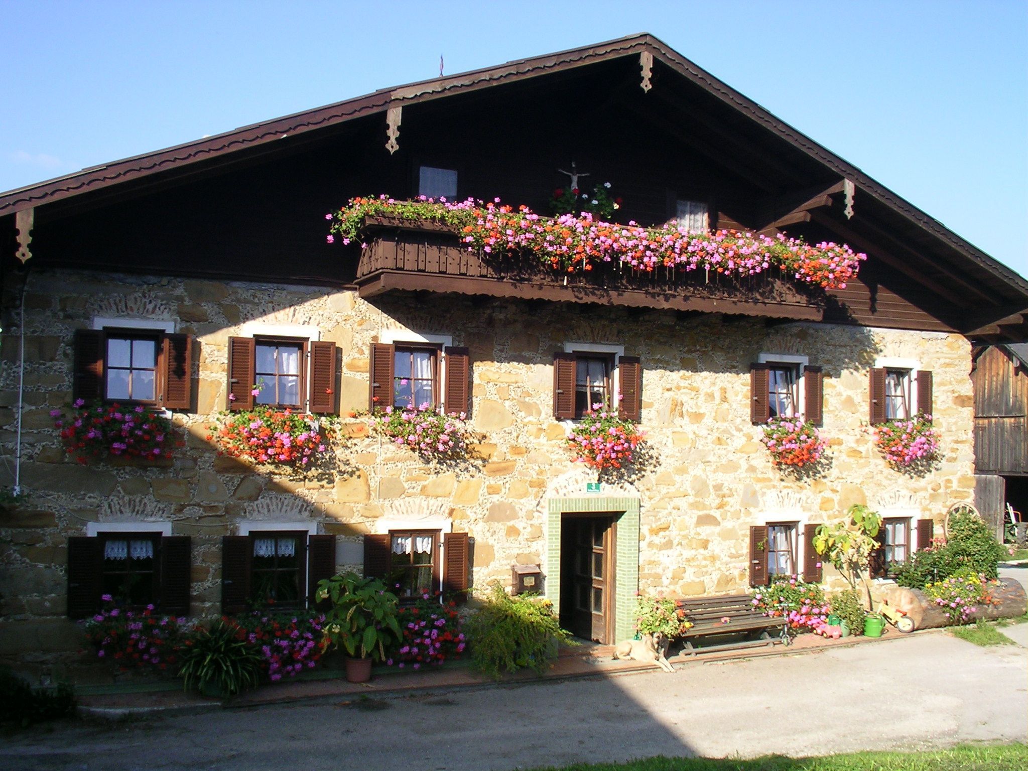 A stone building with multiple windows, some with shutters, and flower boxes on the exterior.