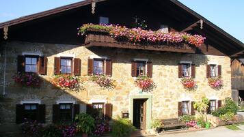 A stone building with multiple windows, some with shutters, and flower boxes on the exterior.