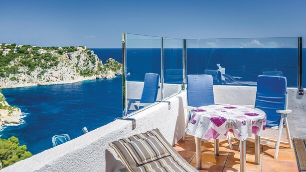 Een terras met een tafel en stoelen met uitzicht op de kust.