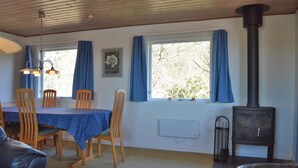 A cozy room with a dining table, chairs, a sofa, a fireplace, and large windows with curtains. - 2 bedroom cozy home in Rømø (Rømø)