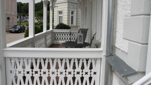 A white balcony with a lattice railing, a small round table, and a chair. - 1st vacation apartment - Villa Fanny (Sassnitz)