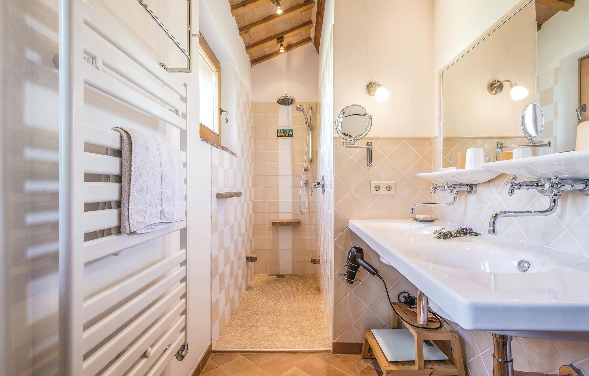 Een badkamer met een douche, wastafel en spiegel.
