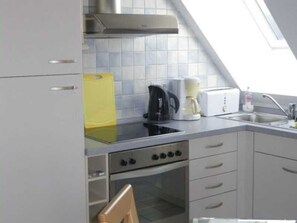Et køkken med gasblus, ovn og kaffemaskine.