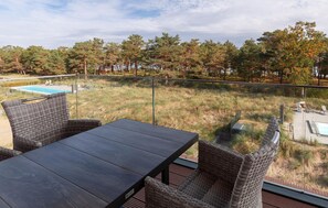 A balcony with wicker furniture, a pool, and a view of trees. - Stunning apartment in Binz with house sea view (Prora/Rügen)
