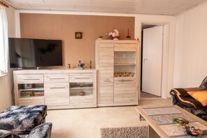 Ein Wohnzimmer mit Fernseher, Holzschrank, Sofa und Couchtisch.