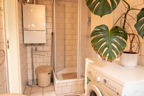 Une salle de bain équipée d’une douche, de toilettes et d’un lave-linge.