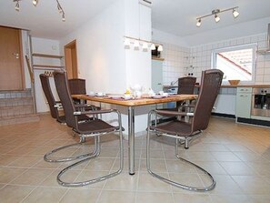 Eine moderne Küche mit Esstisch, vier Stühlen und Fliesenboden.