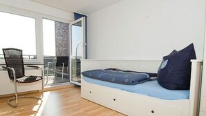 Ein Zimmer mit einem Bett, einem Sessel und einer Schiebetür zu einem Außenbereich.