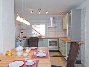 Eine kompakte Küche mit Essbereich, ausgestattet mit einem Herd, Backofen und modernen Leuchten.