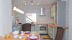 Eine kompakte Küche mit Essbereich, ausgestattet mit einem Herd, Backofen und modernen Leuchten.