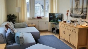 Une chambre moderne équipée d’un canapé, d’une télévision, d’un meuble et d’une fenêtre donnant sur un voilier.