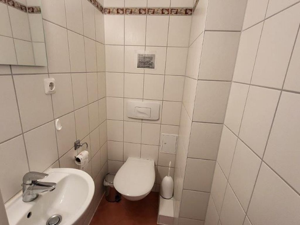 A small bathroom with a sink, toilet, and a mirror.