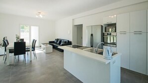 A modern kitchen with a central island, stainless steel appliances, and a dining area with a black leather sofa.