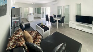 A modern living room with a sofa, a dining area, and a TV.