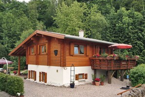 A wooden cabin with a balcony, surrounded by trees. - Apartment 2 - Apartments Am Kupferberg (Walkenried)