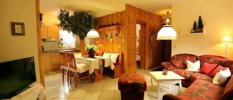 Una sala de estar acogedora con televisor, comedor con mesa y sillas, y un sofá.