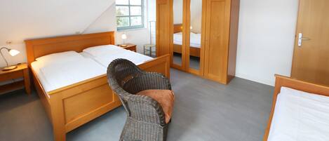 A bedroom with a wooden bed, a chair, a wardrobe, and a window.