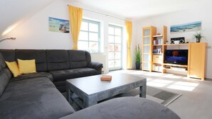 Una sala de estar moderna con un sofá seccional, una mesa de centro y un mueble para TV con televisor de pantalla plana.