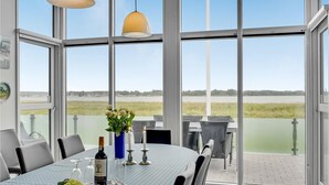 Un coin repas avec une table dressée pour deux personnes, une bouteille de vin et un vase rempli de fleurs.