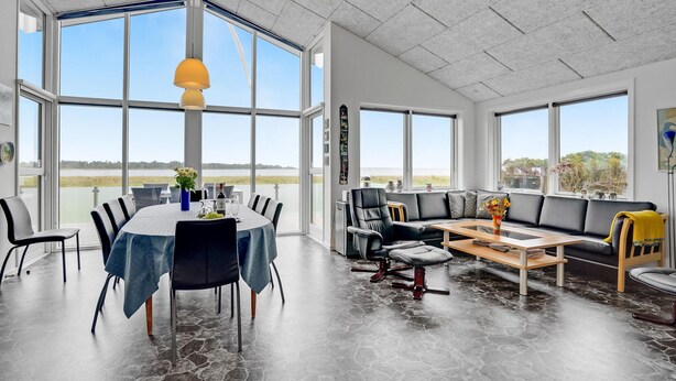 Une pièce spacieuse avec une grande table à manger, un canapé en cuir noir et une table basse.