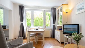 A compact living space with a dining area, a TV, and a small table with a vase.