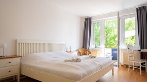 A neatly arranged bedroom with a bed, bedside tables, a chair, and a desk.