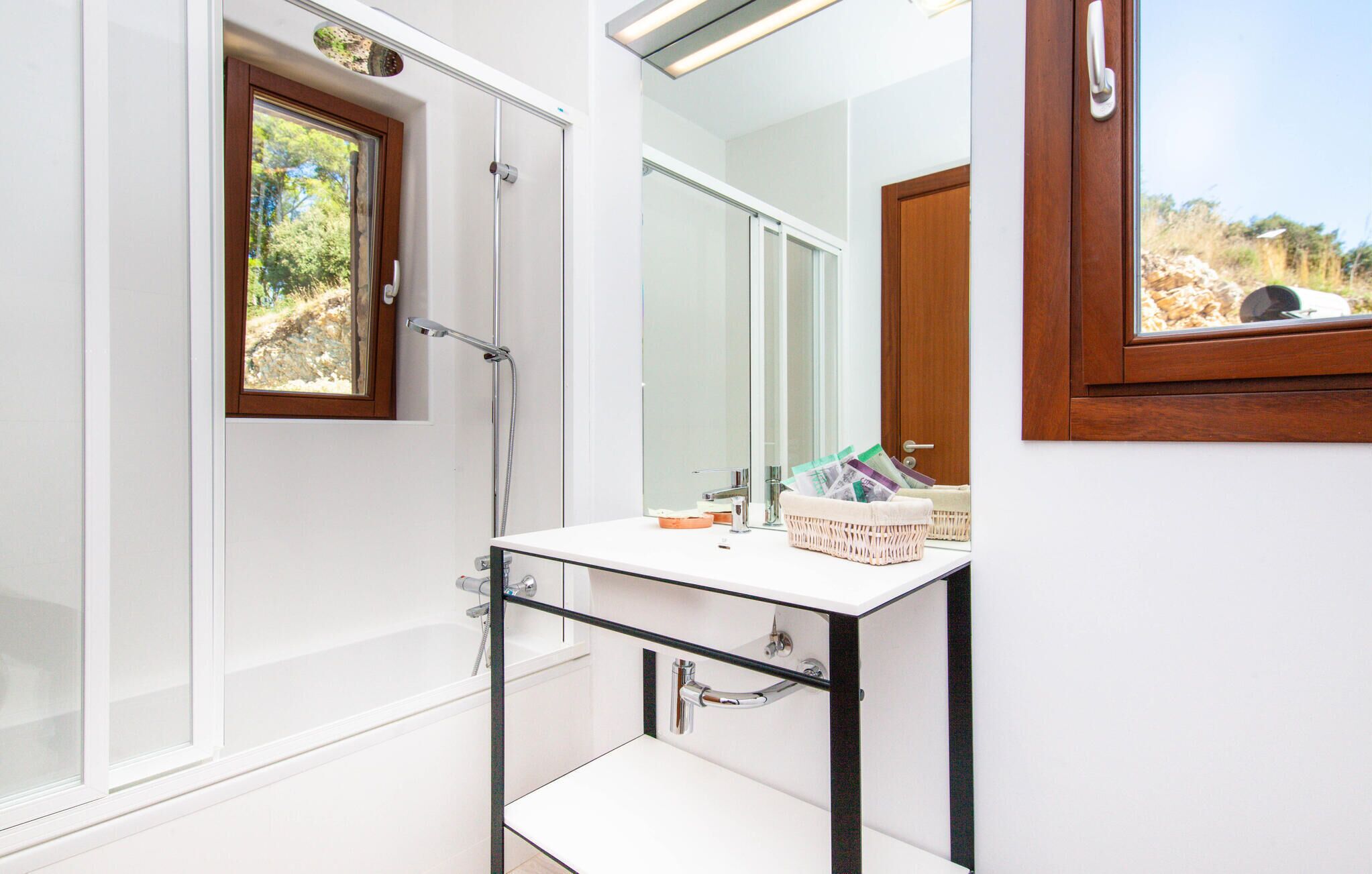 A bathroom with a shower, a sink, a mirror, and a window.