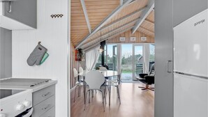 A modern kitchen with white cabinets, a built-in oven, and a dining area with a table and chairs. - Lovely home in Rømø with kitchen (Rømø)