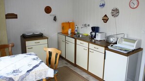 A compact kitchen with a table, chairs, a coffee maker, and a microwave.