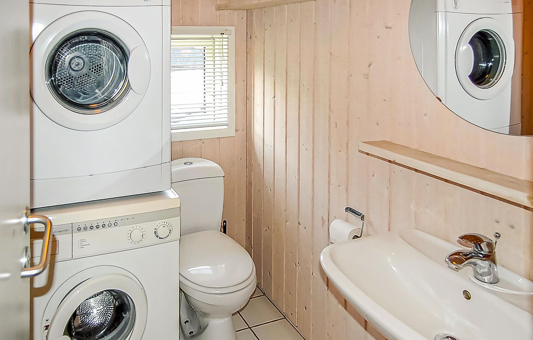Une petite salle de bain équipée d’un lave-linge, de toilettes et d’un lavabo.