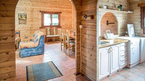 L’intérieur chaleureux d’un chalet en bois comprend un coin repas, une cuisine avec des meubles blancs et un canapé bleu.